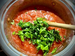 Basilikum zur Tomatensoße hinzufügen