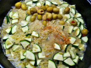 Kritharaki mit Zwiebel, Knoblauch, Gemüsebrühe, Zucchini & Oliven in der Pfanne