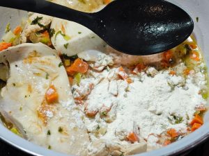 Suppengemüse und Mehl zum Hähnchen geben